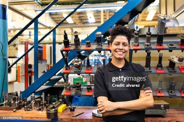 happy female engineer standing in factory - leaning stock pictures, royalty-free photos & images