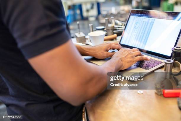 close-up of an engineer working in laptop computer on shop floor - mechanic computer stock pictures, royalty-free photos & images