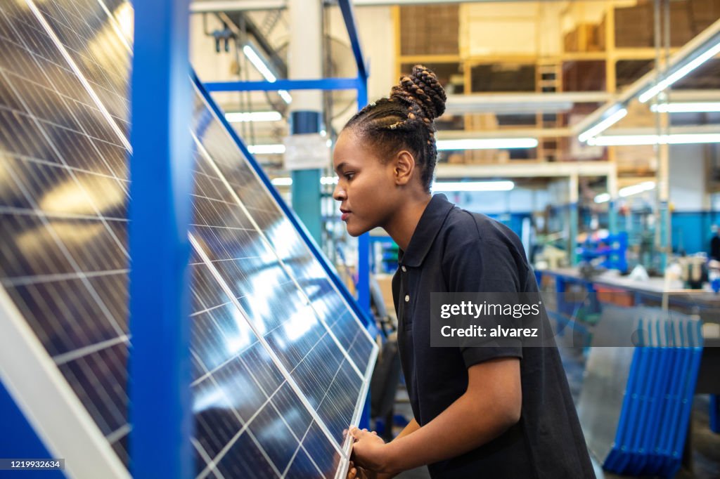 Ingeniero de calidad examinando paneles solares en fábrica