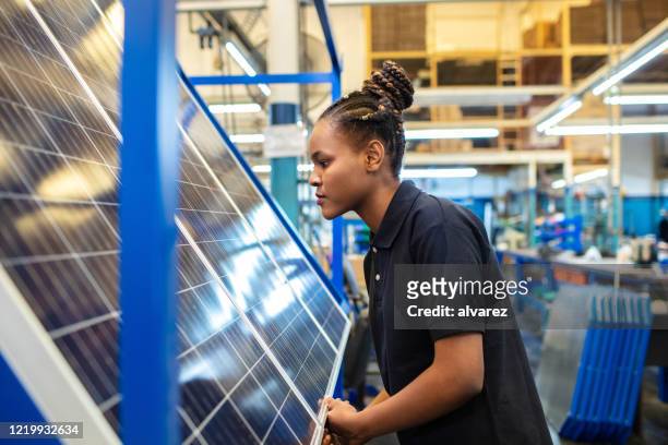 kwaliteitsingenieur onderzoekt zonnepanelen in fabriek - energie industrie stockfoto's en -beelden