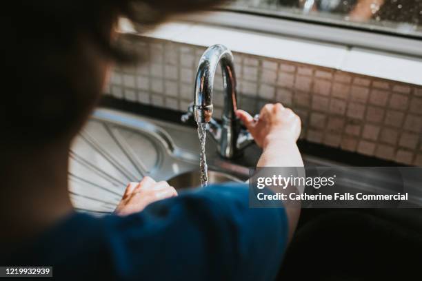 turning the tap on - faucet imagens e fotografias de stock