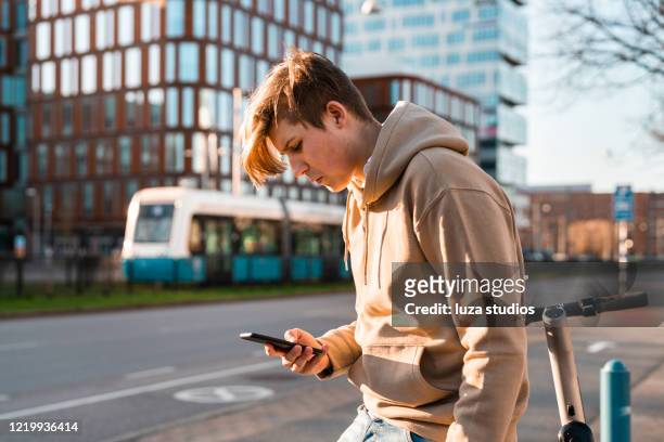 teenager with an electric scooter using his smart phone - goteborg stock pictures, royalty-free photos & images