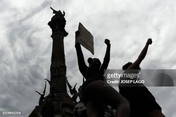 Protesters raise their fists next to the statue of Christopher Columbus during a demonstration in Barcelona, on June 14 as part of the worldwide...