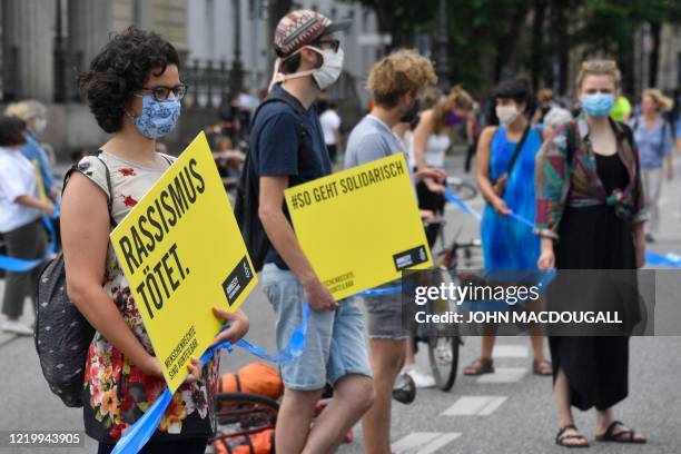 Protester holds a poster that reads "Racism kills" as she takes part in a demonstration organised by the "#unteilbar" movement on June 14, 2020 in...