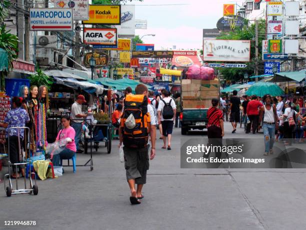 Young traveller with large backpack walks Khao San Road Bangkok Thailand.