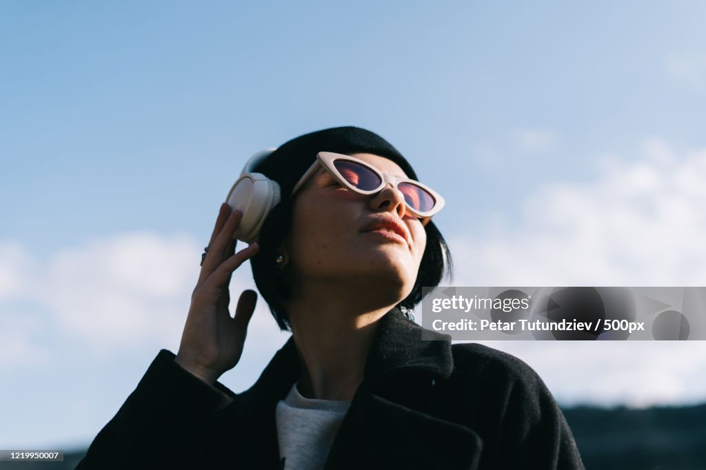 Portrait of young woman listening to music outdoors