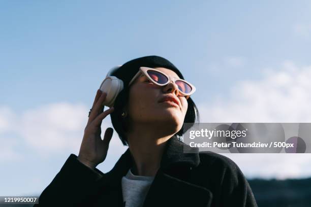 portrait of young woman listening to music outdoors - woman listening to music imagens e fotografias de stock