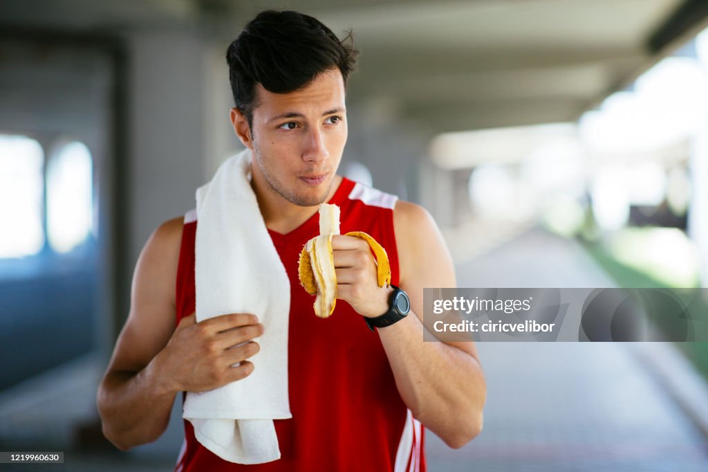 Hombre atlético comiendo plátano después del entrenamiento al aire libre