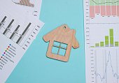 Profitable investment. Market analysis. Buying a property. House Minifigure,  graphs and chartsc on blue pastel background