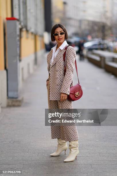 Guest wears sunglasses, a white shirt, a jacket with printed patterns, a red leather bag from Etro, flare pants, white leather pointy boots, outside...