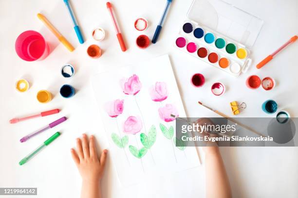 close up of child's hands drawing at white paper. - baby paint stock-fotos und bilder