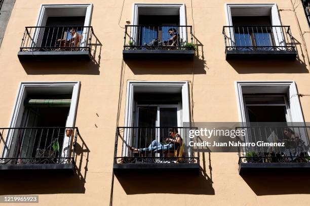 People sunbathing on their balconies while working and reading on April 20, 2020 in Madrid, Spain. Starting last week, some businesses deemed...