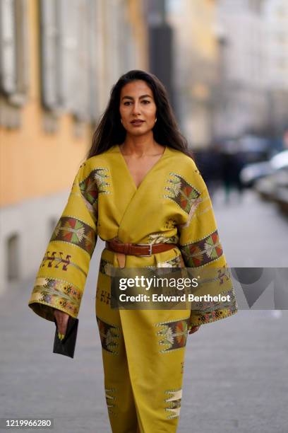 Guest wears a yellow double breasted kimono dress with flared sleeves, a brown leather belt, outside Etro, during Milan Fashion Week Fall/Winter...
