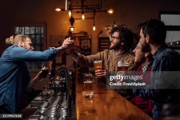 groep mensen die bier bij de bar drinken die de barman begroet - man sipping beer smiling stockfoto's en -beelden