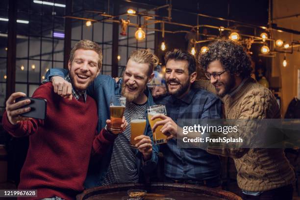 happy gatherings in de pub: groep van gelukkige jonge mannen die een selfie nemen terwijl ze bier drinken - man sipping beer smiling stockfoto's en -beelden