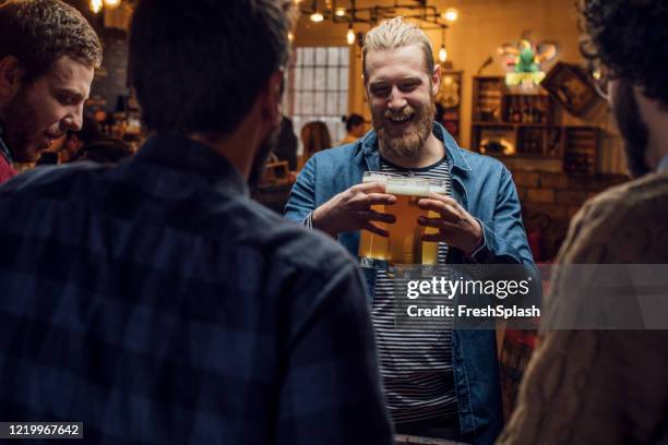 happy blond hipster man brengen bier voor zijn vrienden in een pub - man sipping beer smiling stockfoto's en -beelden