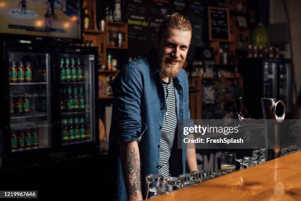 portrait of a bearded blond hipster bartender smiling - hipster barkeeper stock pictures, royalty-free photos & images