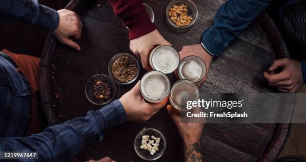 mani di persone che brindano con la birra in un pub - bar overhead foto e immagini stock