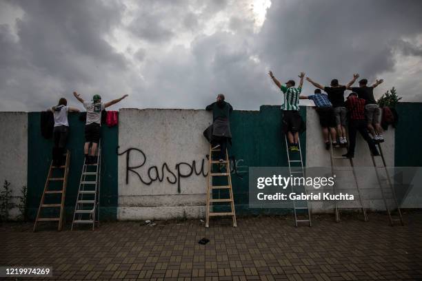 Football fans stand on ladders to peer over a wall as they watch a Czech First League match between Bohemians 1905 and FK Jablonec at Dolicek Stadium...