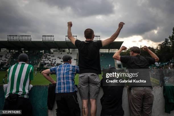 Football fans stand on ladders to peer over a wall as they watch a Czech First League match between Bohemians 1905 and FK Jablonec at Dolicek Stadium...