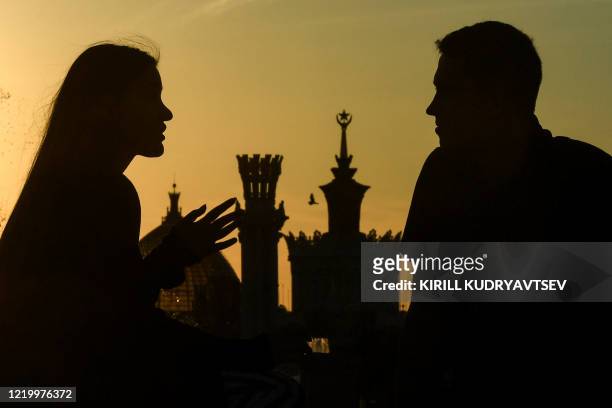 Couple chats in the sunset in front of the famous Druzhba Narodov fountain in the All-Russia Exhibition Centre , a trade show and amusement park in...