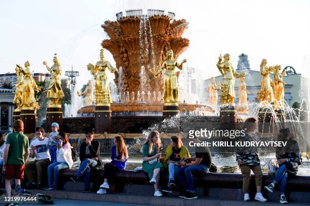 People rest in front of the famous Druzhba Narodov fountain in the All-Russia Exhibition Centre , a trade show and amusement park in Moscow on June...