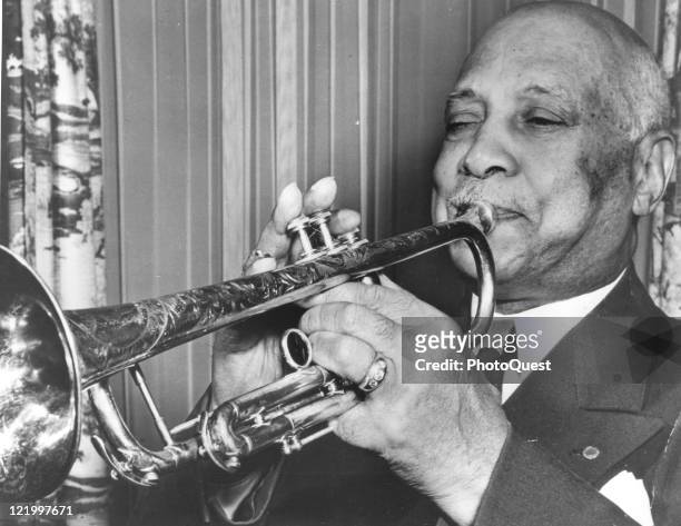 Portrait of jazz and blues pioneer W.C. Handy , blowing on his trumpet, mid twentieth century.