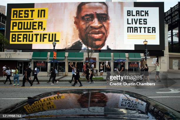 People walk past an electronic sign with an image of George Floyd near Centennial Olympic Park on June 14, 2020 in Atlanta, Georgia. Rayshard Brooks...
