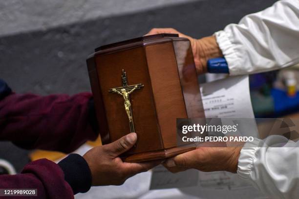 Man receives the urn containing the ashes of his father, a victim of COVID-19, at the crematorium of the Iztapalapa pantheon in Mexico City, on June...