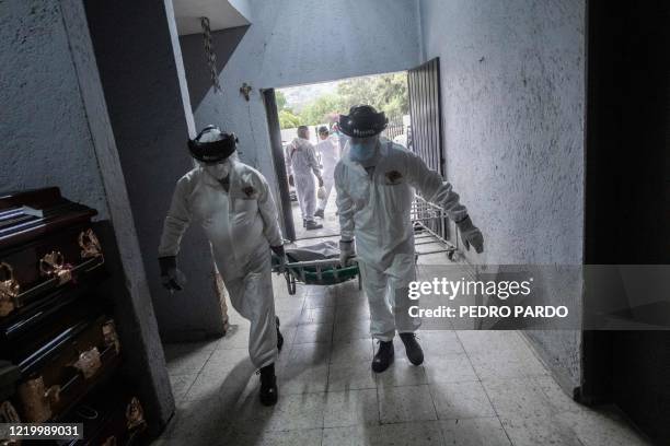 Employees of the Iztapalapa pantheon take a body bag with the remains of a victim of COVID-19 to the crematorium, in Mexico City, on June 11 amid the...