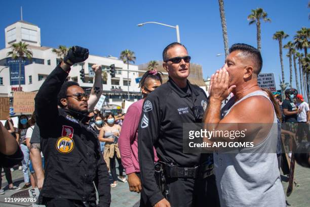 Man chants to the crowd "All lifes matter" while a Police officer stands in his way from protesters during a demonstration against Police brutality...