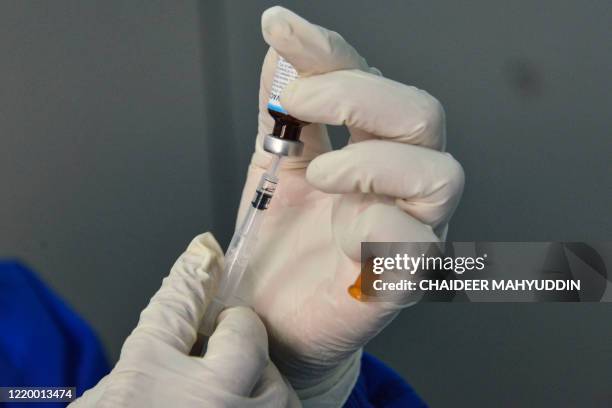 Member of the medical staff clad in protective gear prepares to give an infant the Bacillus CalmetteGuérin vaccine for tuberculosis at a community...