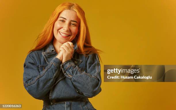 glückliche schöne frau mit orangen haaren vor dem gelben hintergrund - jeans latzhose frau stock-fotos und bilder