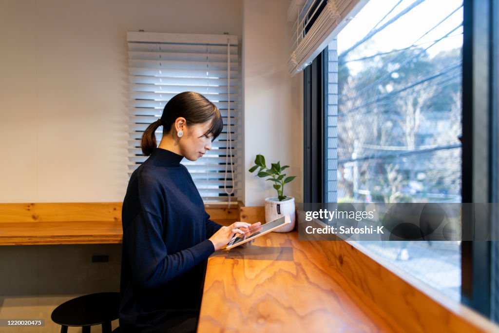 Junge Frau mit Digitaltablett im Café