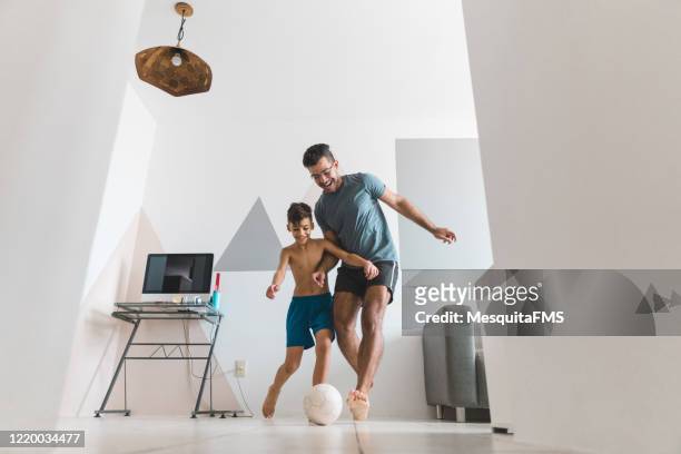 father and son playing soccer in the living room - quarantine fun stock pictures, royalty-free photos & images