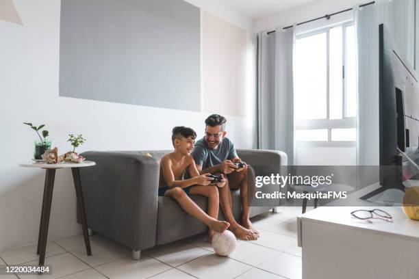 padre e hijo jugando videojuegos - brazilian playing football fotografías e imágenes de stock