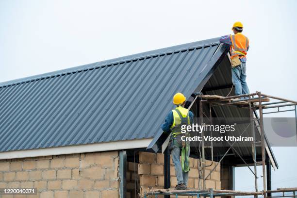 construction worker wearing safety harness are working on the roof house. - lift roof bildbanksfoton och bilder