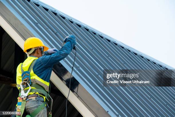 construction worker wearing safety harness are working install new roof. - dakdekker stockfoto's en -beelden