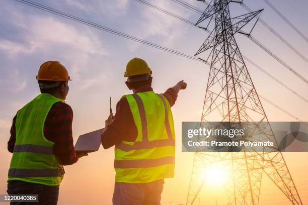 asian manager engineering and worker in standard safety uniform working inspect the electricity high voltage pole. - power grid stock-fotos und bilder