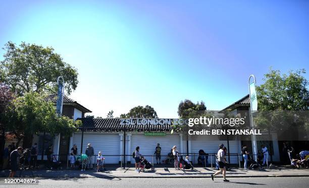 Visitors stand apart to adhere to the British government's current social distancing guidelines of two meters , as they queue to enter London Zoo in...