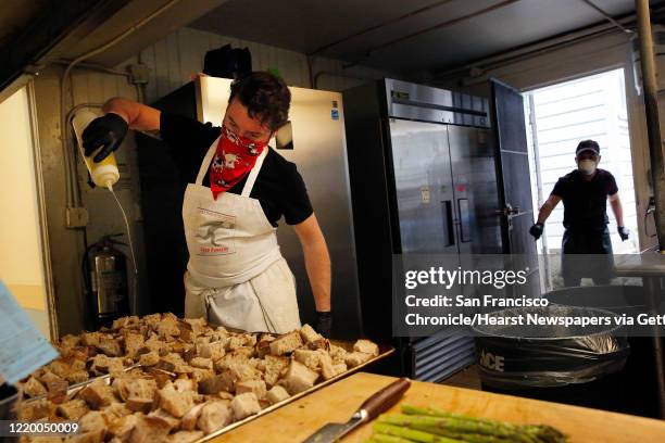 Todd Corboy , Food Runner chef, drizzles oil on chunks of bread while working in the new Food Runners"u2019 kitchen along with Ariel Alonso and other...