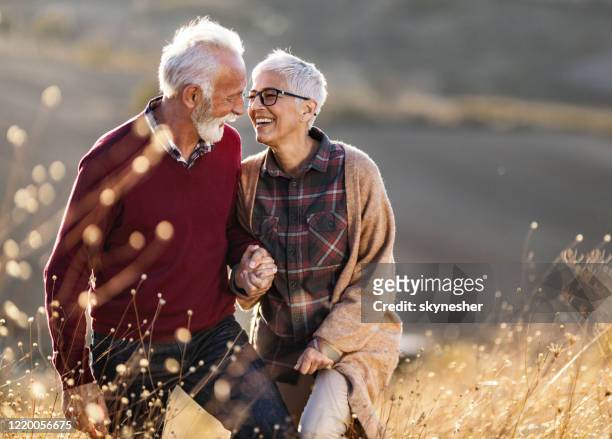 felice coppia senior che parla mentre cammina su una collina nella giornata autunnale. - coppia anziana foto e immagini stock