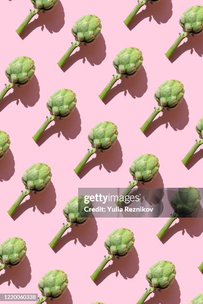 repeated artichokes on the pink background - artichoke stock pictures, royalty-free photos & images