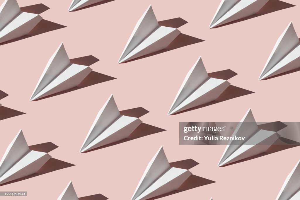 Repeated paper airplanes on the pink background