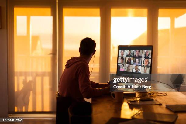young man distracted while on video call from his home during lockdown - lockdown stock pictures, royalty-free photos & images