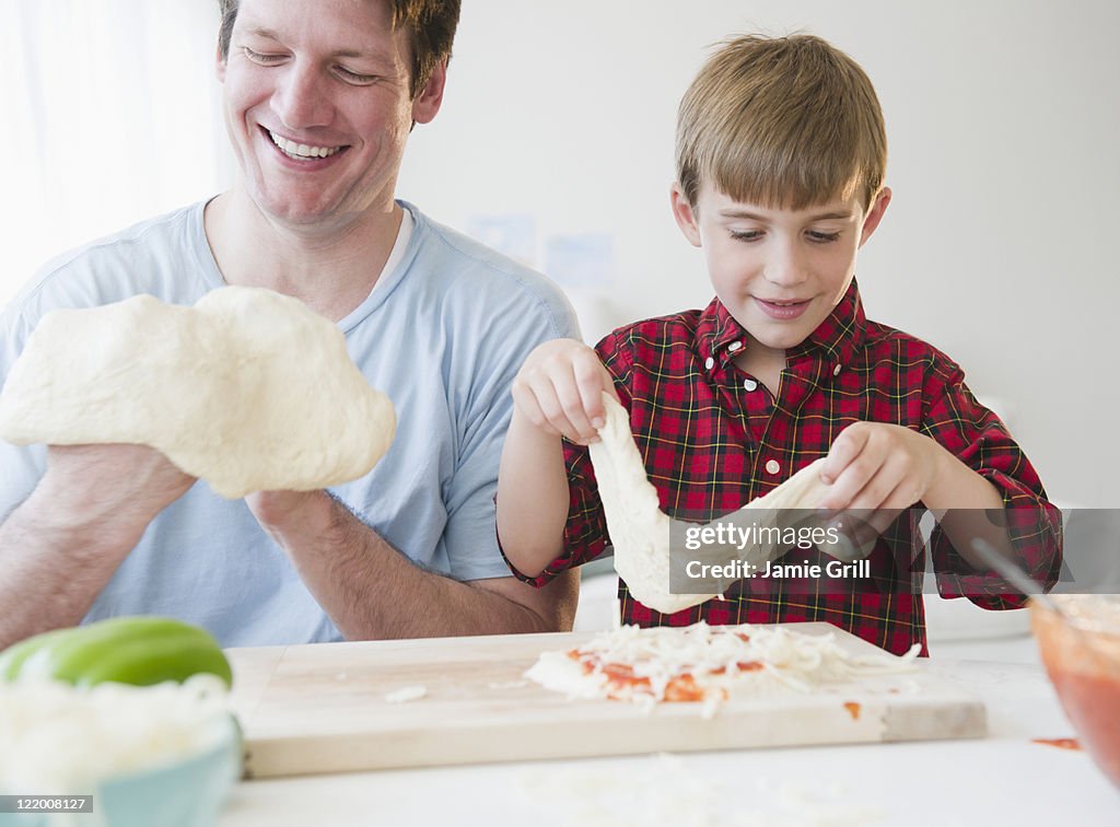 Father and son making pizza together