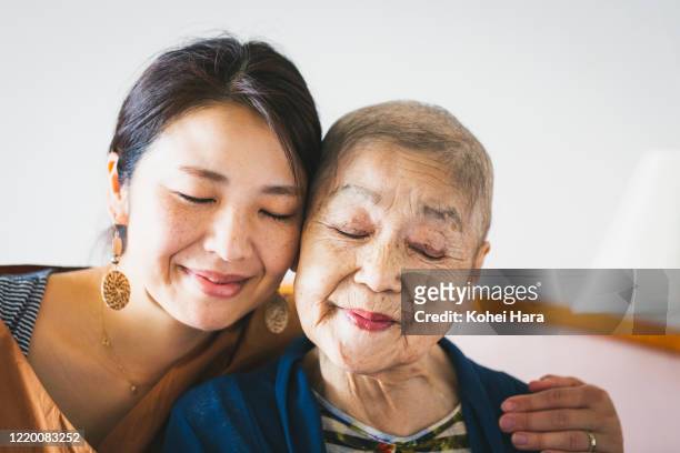 portrait of old mother with cancer and her middle aged daughter - cancer illness stock pictures, royalty-free photos & images