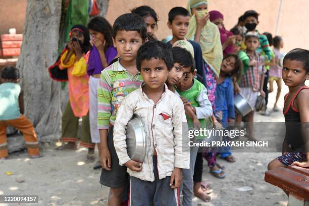 Children from a slum stand in queue to get free food after the government eased a nationwide lockdown as a preventive measure against the COVID-19...