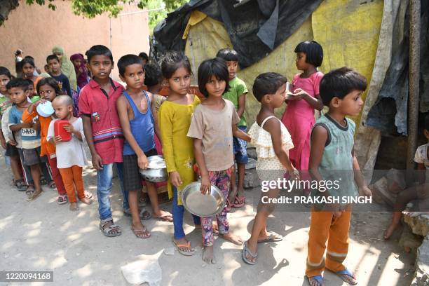 Children from a slum stand in queue to get free food after the government eased a nationwide lockdown as a preventive measure against the COVID-19...