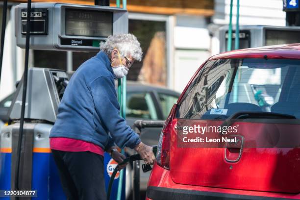 Woman fills the petrol tank of her car at an independent petrol station on April 21, 2020 in London, England. The slump in demand for oil due to the...